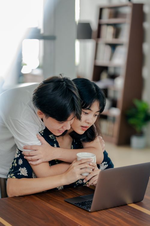 Free A couple shares a loving moment while working on a laptop indoors. Stock Photo
