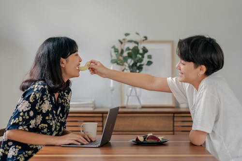 Photo of Couple Smiling While Sitting by the Wooden Table