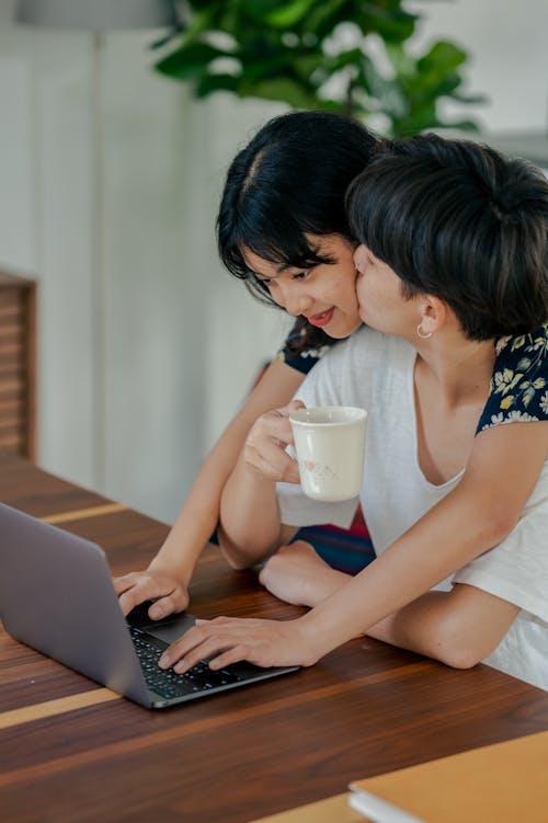 Free Photo of Man Kissing Her Woman While Using Laptop Stock Photo