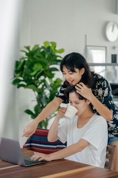 一对幸福的夫妇在舒适的室内环境中，一边享用咖啡，一边在笔记本电脑上工作