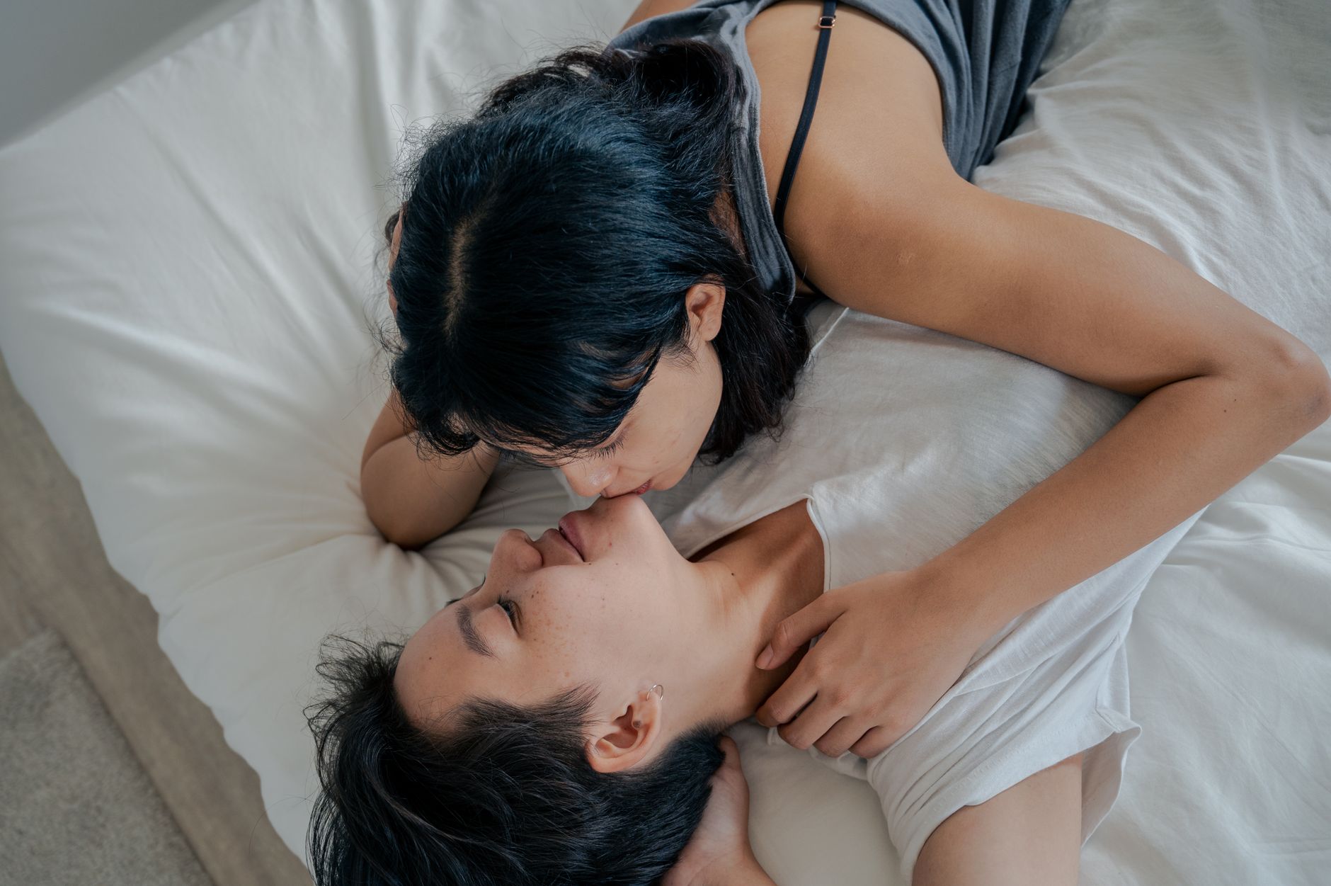 A loving couple sharing an intimate moment while lying on a bed indoors.