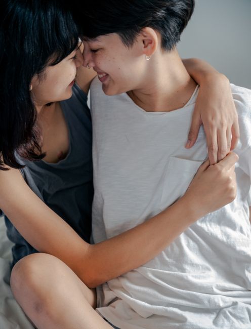 Close-up of two women embracing and smiling, showcasing affection and intimacy in a tender moment.