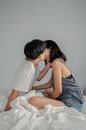 一对恩爱的夫妇坐在卧室舒适的床上，温柔地亲吻着