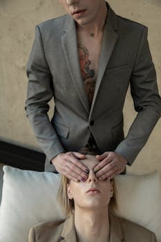 这幅艺术肖像以一位身穿灰色西装、遮住他人眼睛的人物为特色，其主题为概念性表达