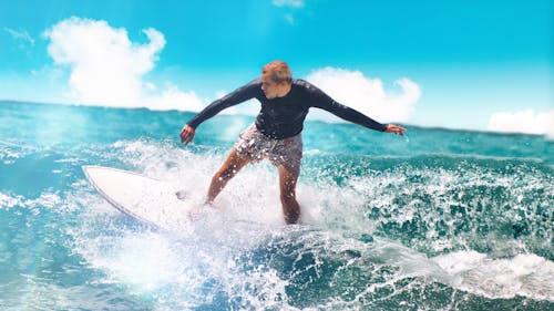 A Man in Black Wet Suit Surfing on the Sea Waves