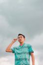 一位戴着眼镜的年轻人自信地以多云的天空为背景摆出姿势