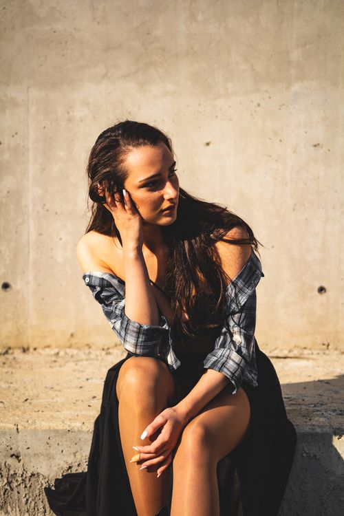 Free Young woman posing outdoors with hand on head, wearing a stylish outfit. Stock Photo