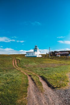 蔚蓝的天空下，一座风景如画的灯塔矗立在绿草如茵的乡村中