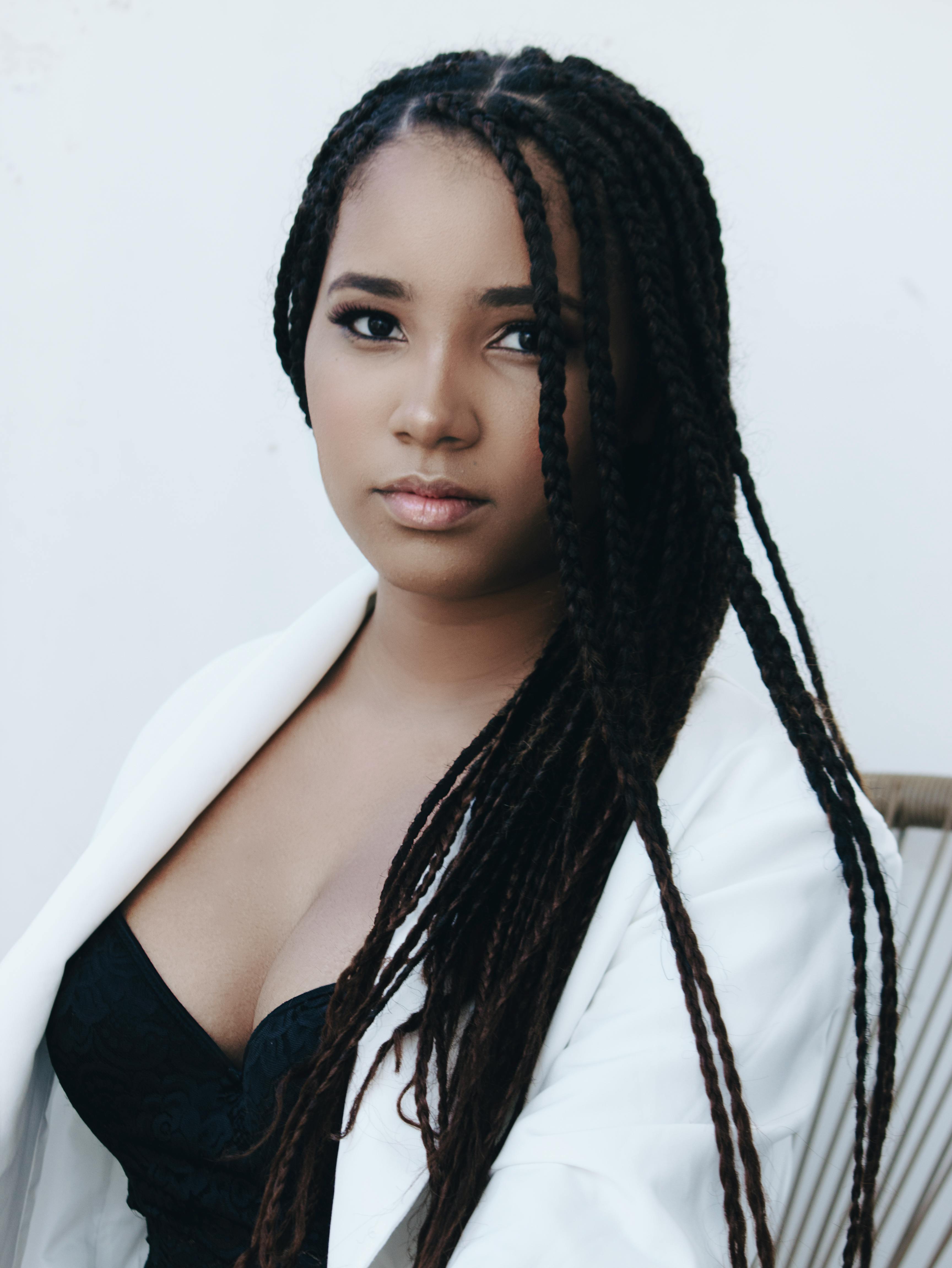 Elegant portrait of a woman with braided hair wearing a white jacket.