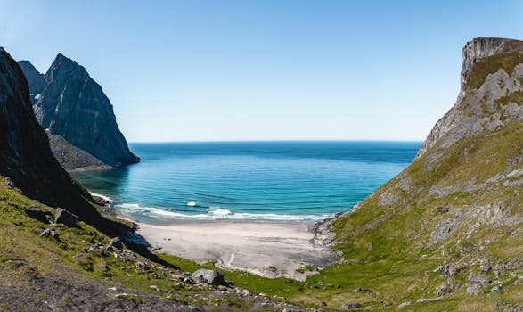 A breathtaking view of Lofoten's pristine beach and turquoise waters surrounded by majestic cliffs.
