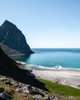 Breathtaking view of a serene beach next to a towering mountain in Moskenes, Norway.