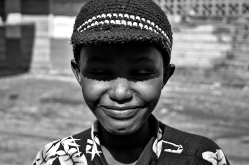 Grayscale Photo of Boy Wearing Knit Cap While Smiling