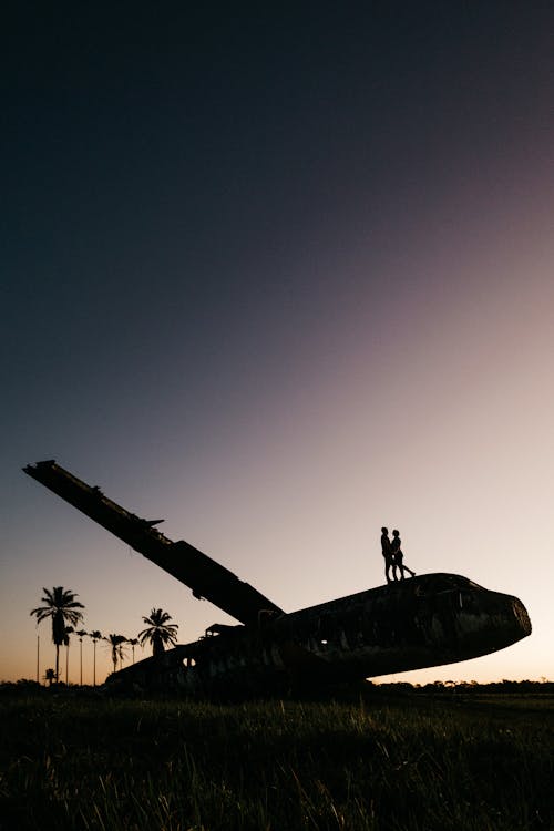 Silhouettes De Couple Méconnaissables Embrassant Un Avion Endommagé Pendant La Nuit