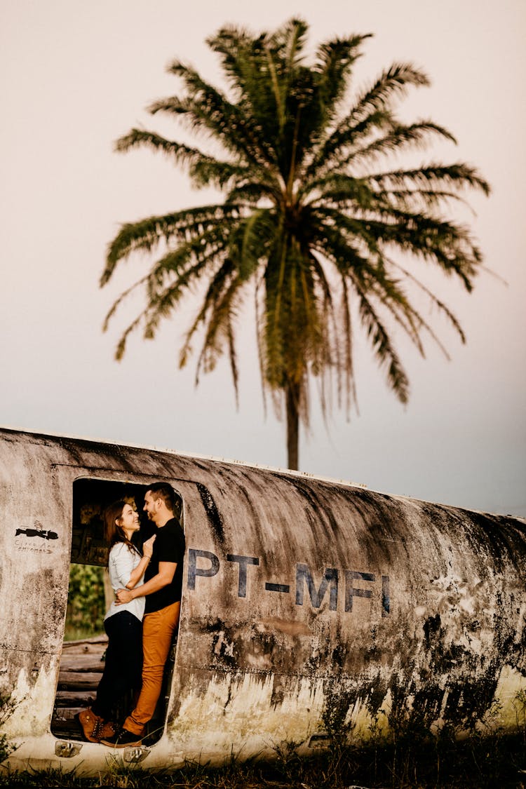 Anonymous Couple Of Travelers Embracing In Old Airplane After Accident