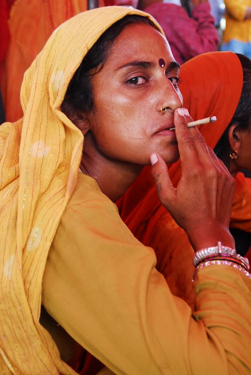 Woman in Yellow Long Sleeves Smoking Cigarette