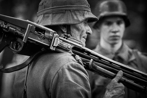 Grayscale Photo of Man Holding Rifle