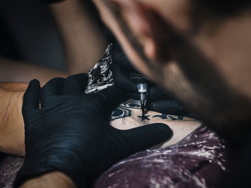 Artist in black gloves finishing a fresh tattoo