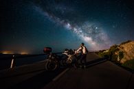 在一条僻静的道路上，一个骑摩托车的人凝视着星空，看到了令人叹为观止的银河夜景