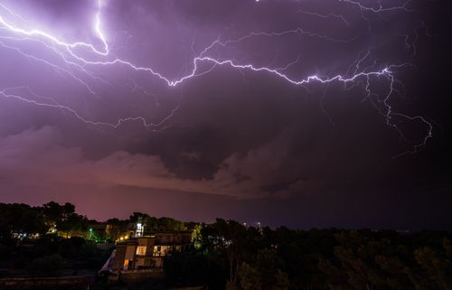 Free Captivating view of a powerful lightning storm illuminating the night sky over a small town. Stock Photo