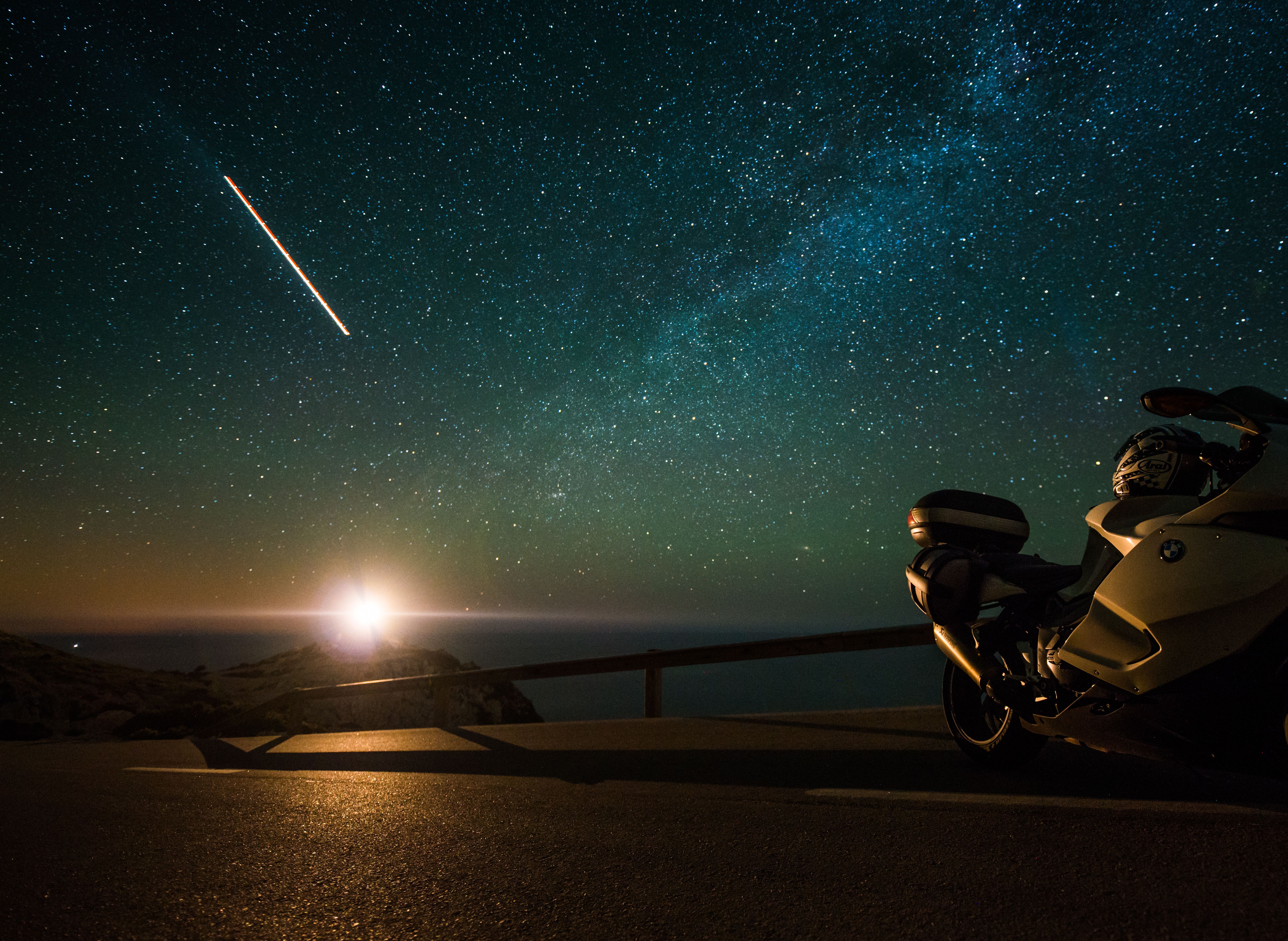 一辆摩托车停在风景优美的星空下，头顶银河，捕捉着旅行与冒险的瞬间