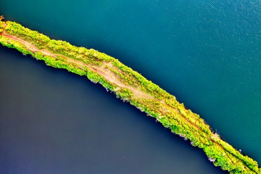 Stunning aerial shot of a lush, green island surrounded by blue waters in Banten, Indonesia.