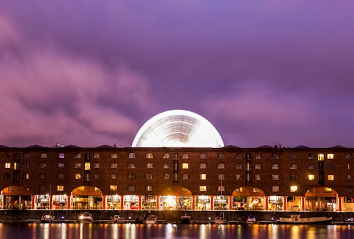 Illuminated Albert Dock with ferris wheel reflection at night in Liverpool, UK. by Neil Martin