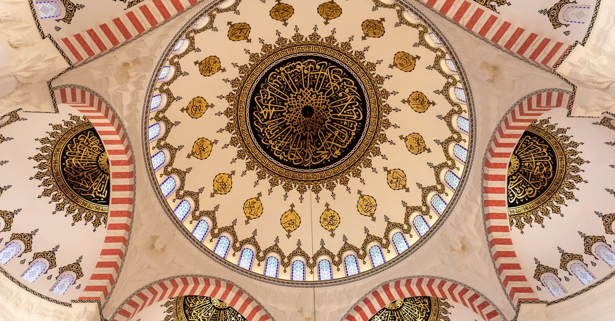 Stunning symmetrical view of an ornately decorated mosque ceiling in Sharjah, UAE.