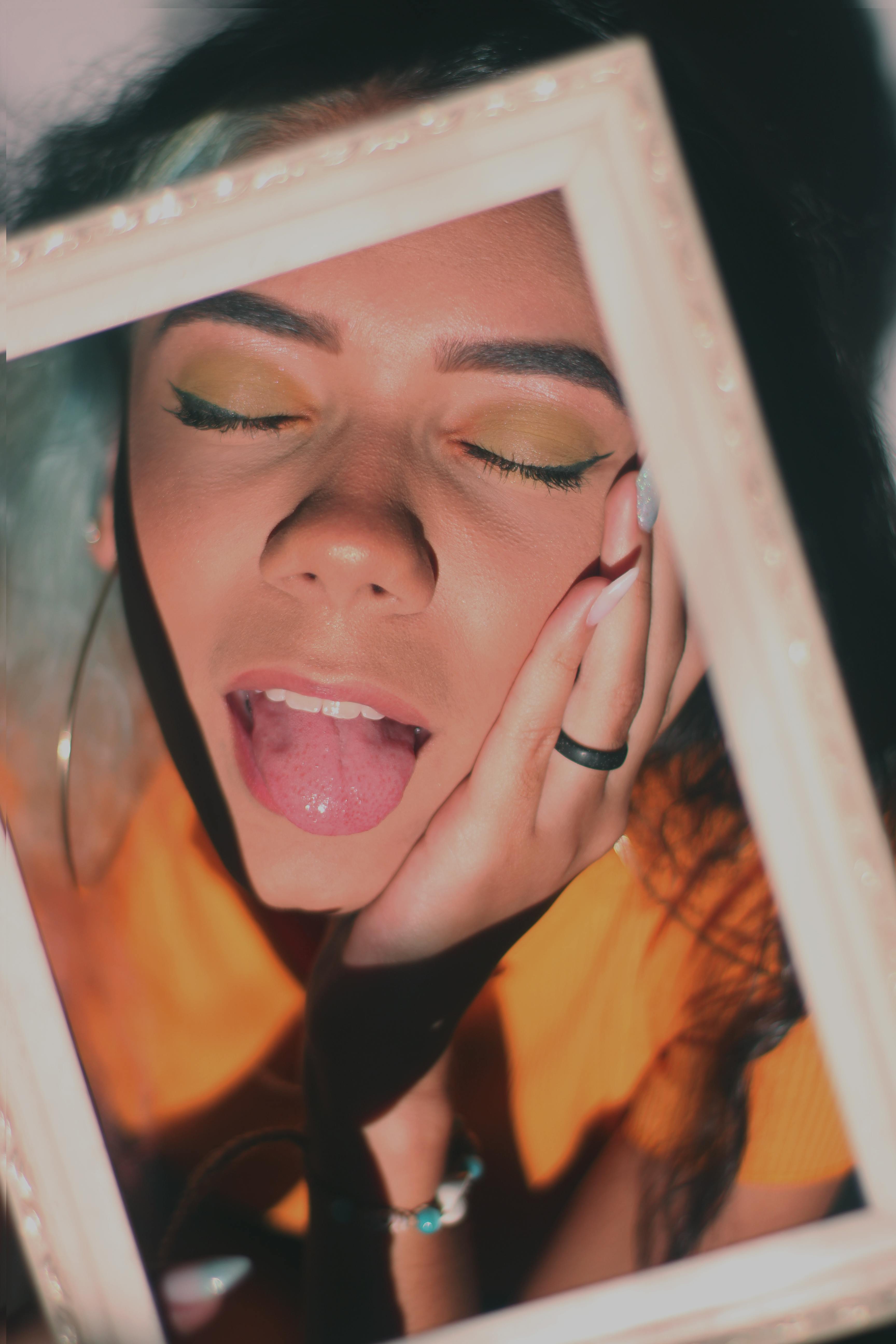Vibrant portrait of a woman with closed eyes and playful expression framed creatively.