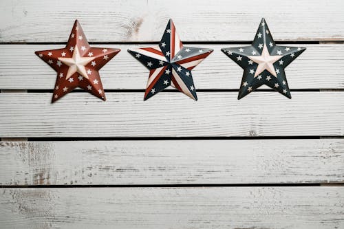 Top view of row of figurines of red and blue raised stars on white striped wooden table