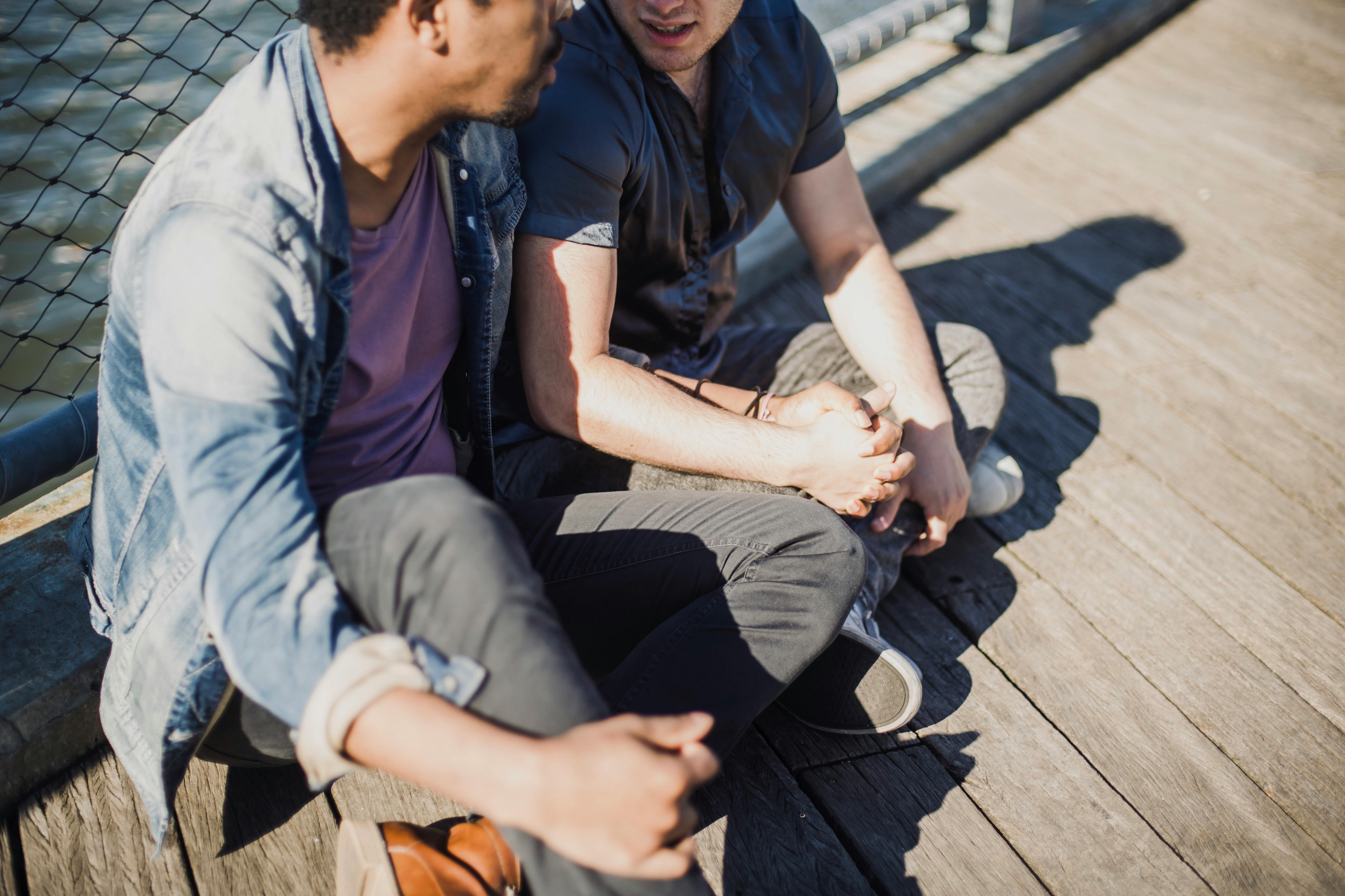 two men sitting and holding hands