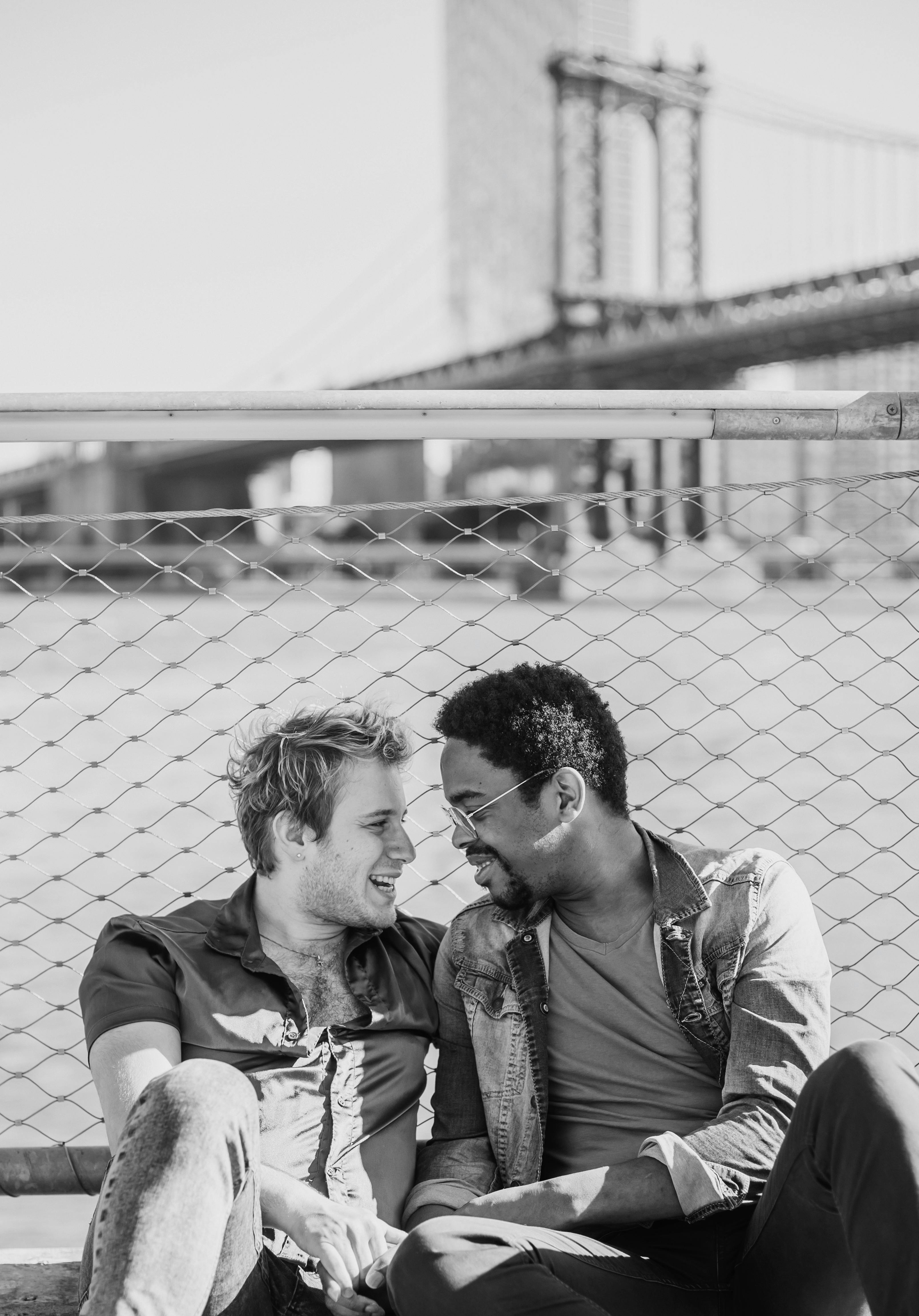 grayscale photo of two men sitting and looking at each other