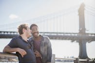 两个朋友在城里的桥边，享受着阳光明媚的一天，分享着笑声与微笑