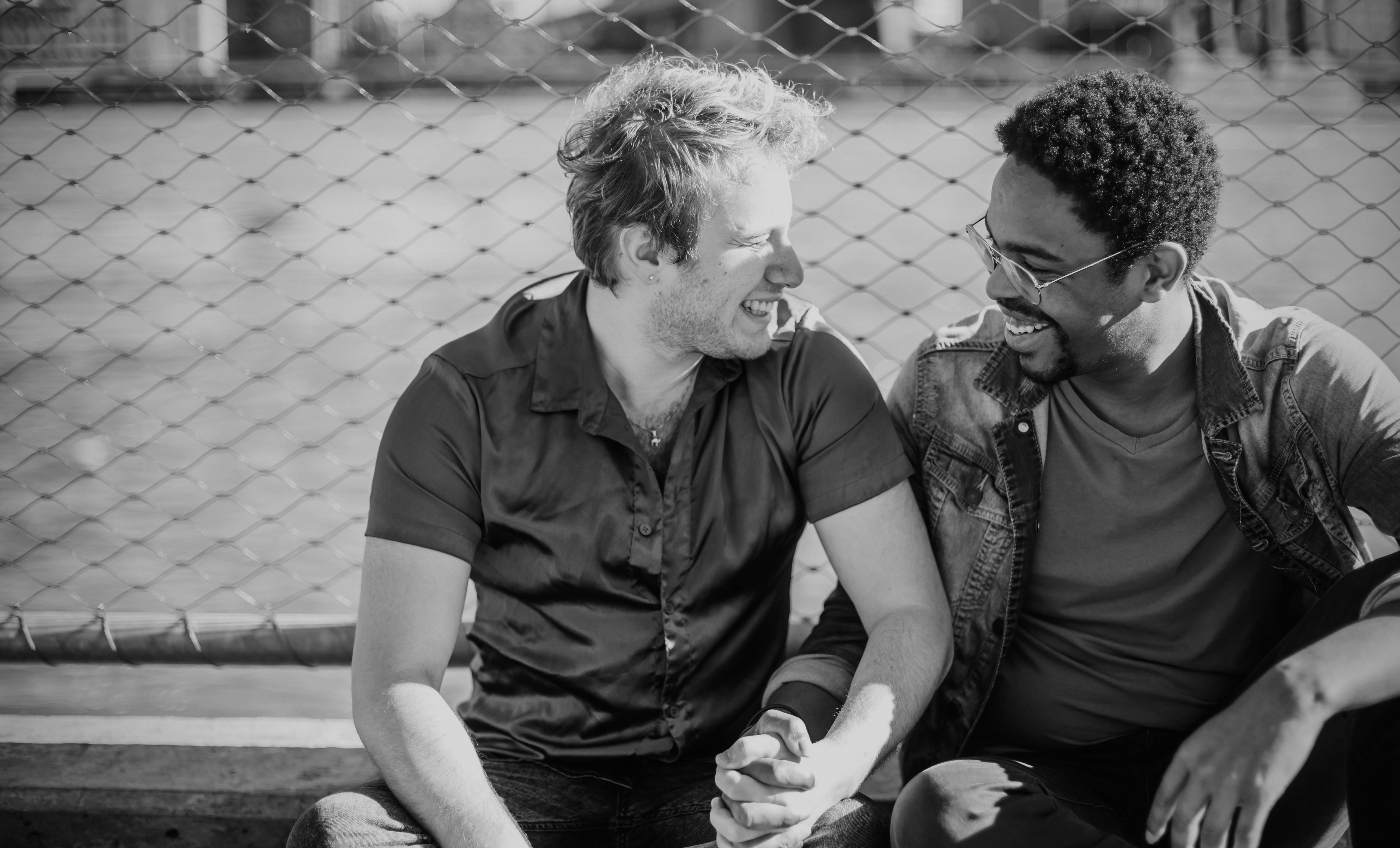 grayscale photo of two men holding hands