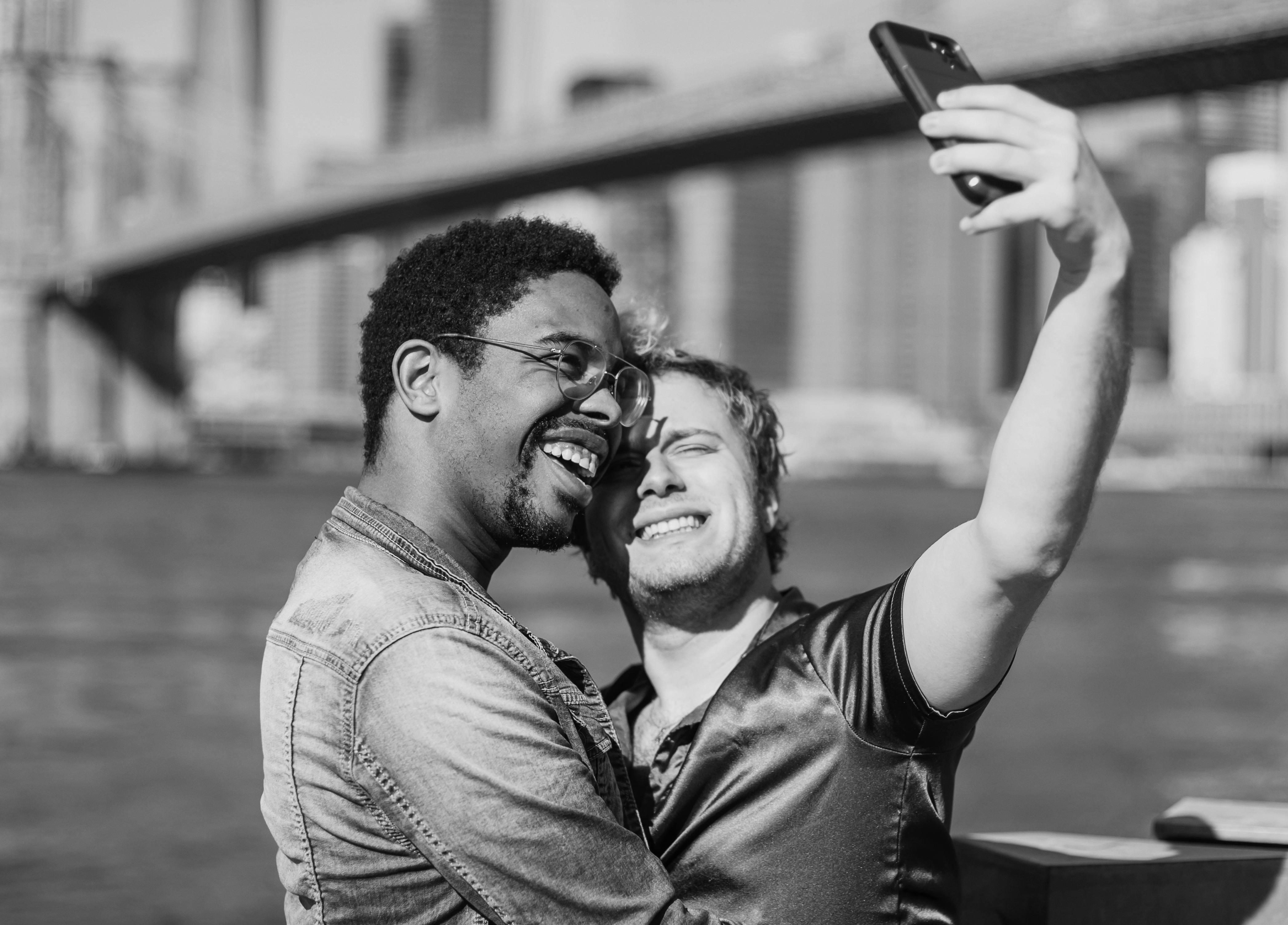 grayscale photo of two men taking a selfie