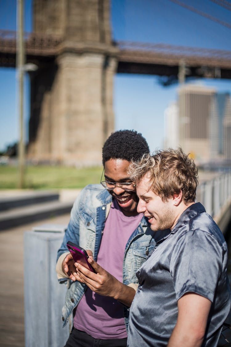 Two Men Looking At Smart Phone And Laughing