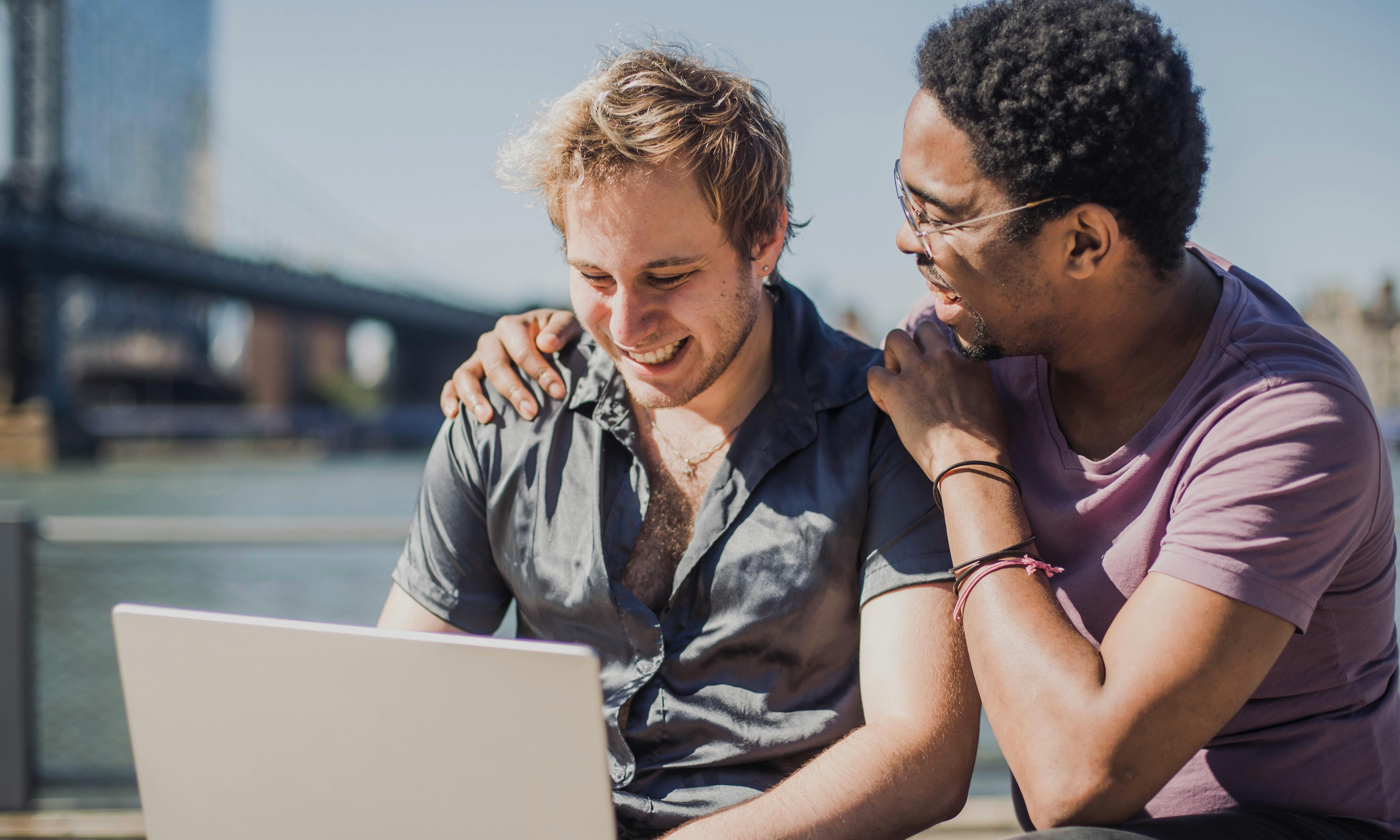 happy men using a laptop outside