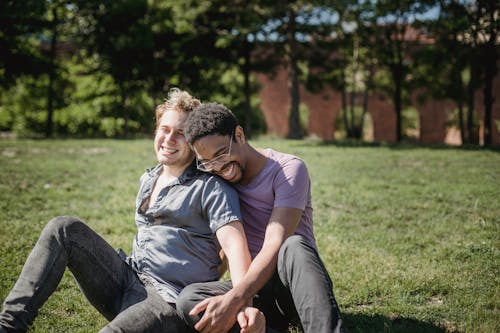 Two Men Sitting on the Grass and Being Affectionate