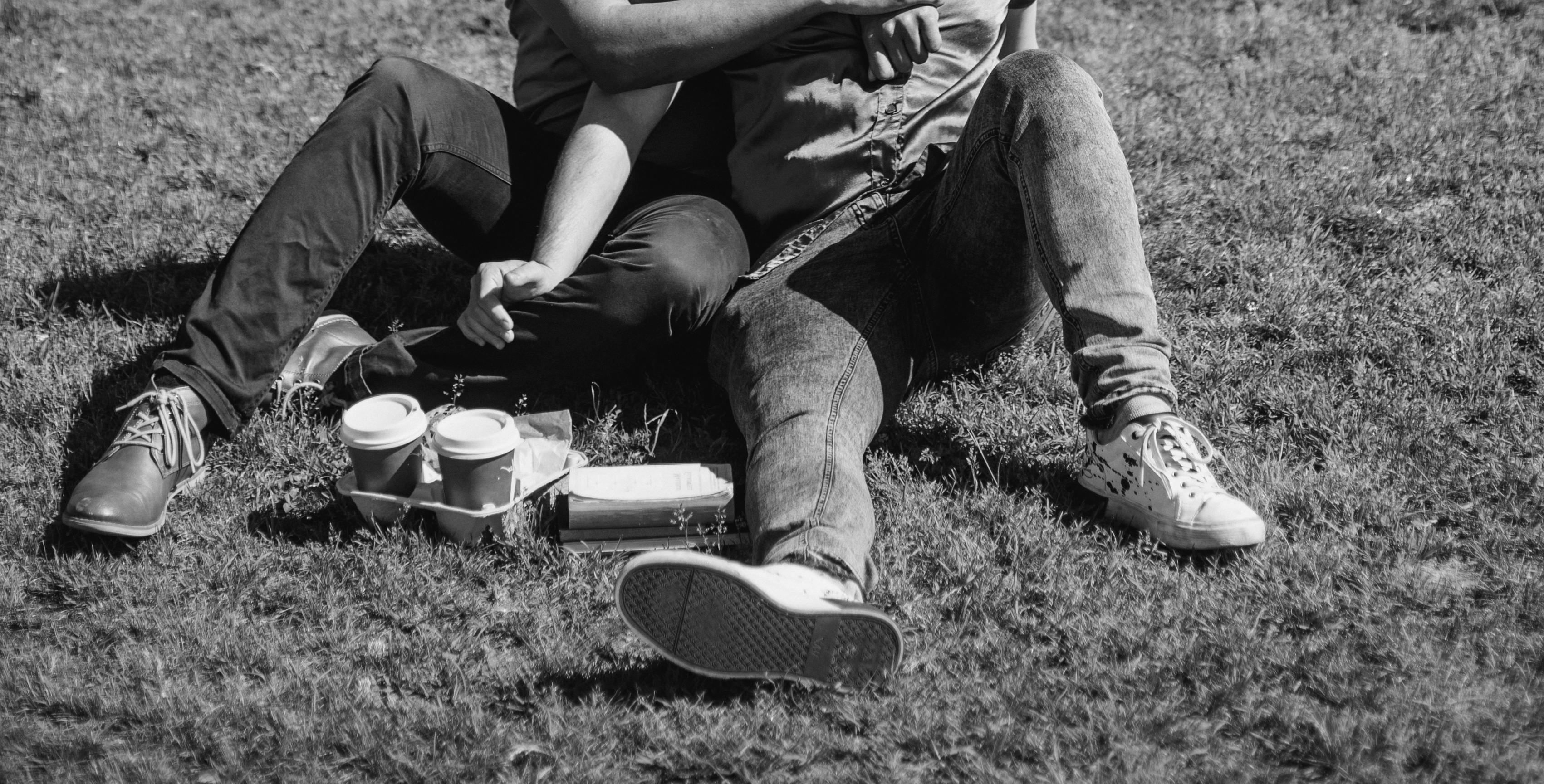 这是一幅灰度图像，一对夫妇坐在户外的草地上一起喝咖啡