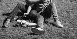 这是一幅灰度图像，一对夫妇坐在户外的草地上一起喝咖啡