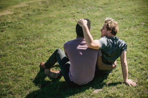 Free Two Men Sitting on the Grass and Being Affectionate Stock Photo