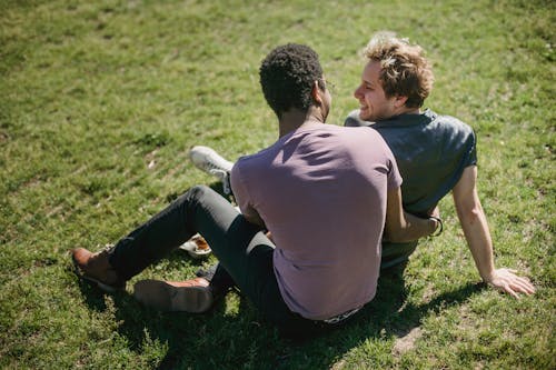 Two Men Sitting on the Grass and Being Affectionate