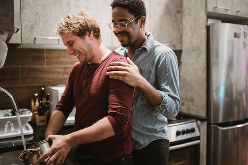 Free A happy interracial gay couple enjoying quality time together while cooking in a modern kitchen. Stock Photo