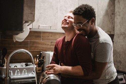 Free Happy interracial gay couple sharing an affectionate moment in the kitchen. Stock Photo