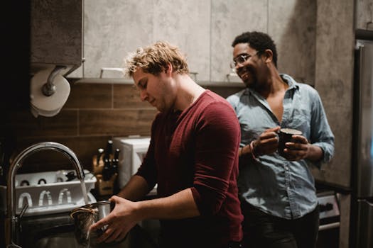 Two men enjoying casual conversation while doing kitchen chores together.