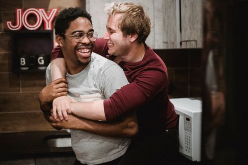 Free Two men sharing a happy embrace in a cozy indoor setting. Stock Photo