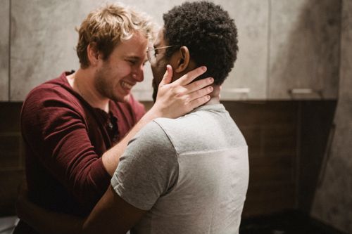 Free A happy interracial gay couple embracing warmly in a cozy kitchen setting, expressing love and affection. Stock Photo