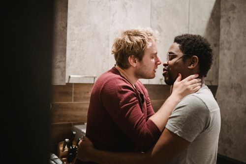 Free A loving interracial LGBTQ couple embraces tenderly in a cozy indoor setting. Stock Photo