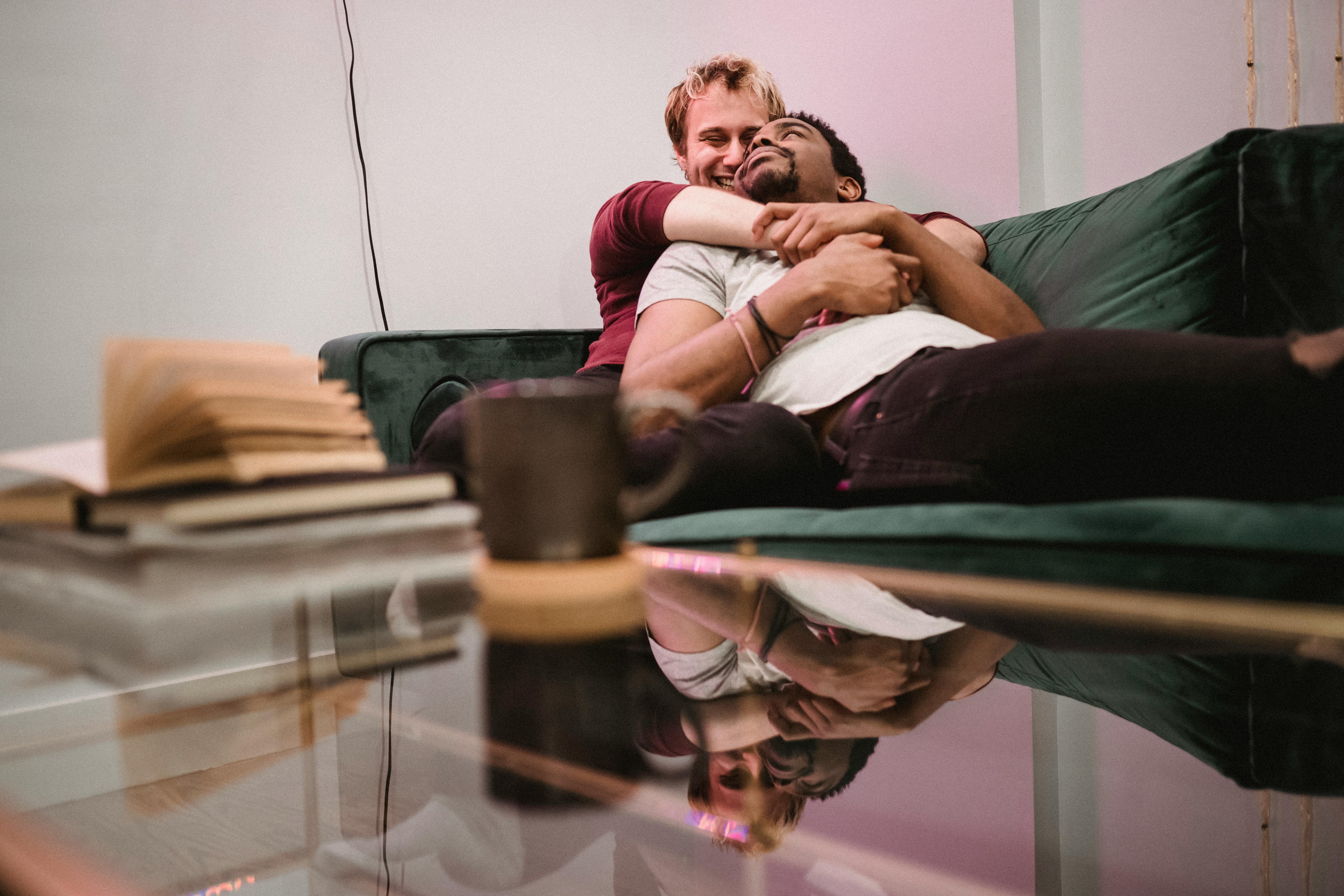 two men lying together on a couch