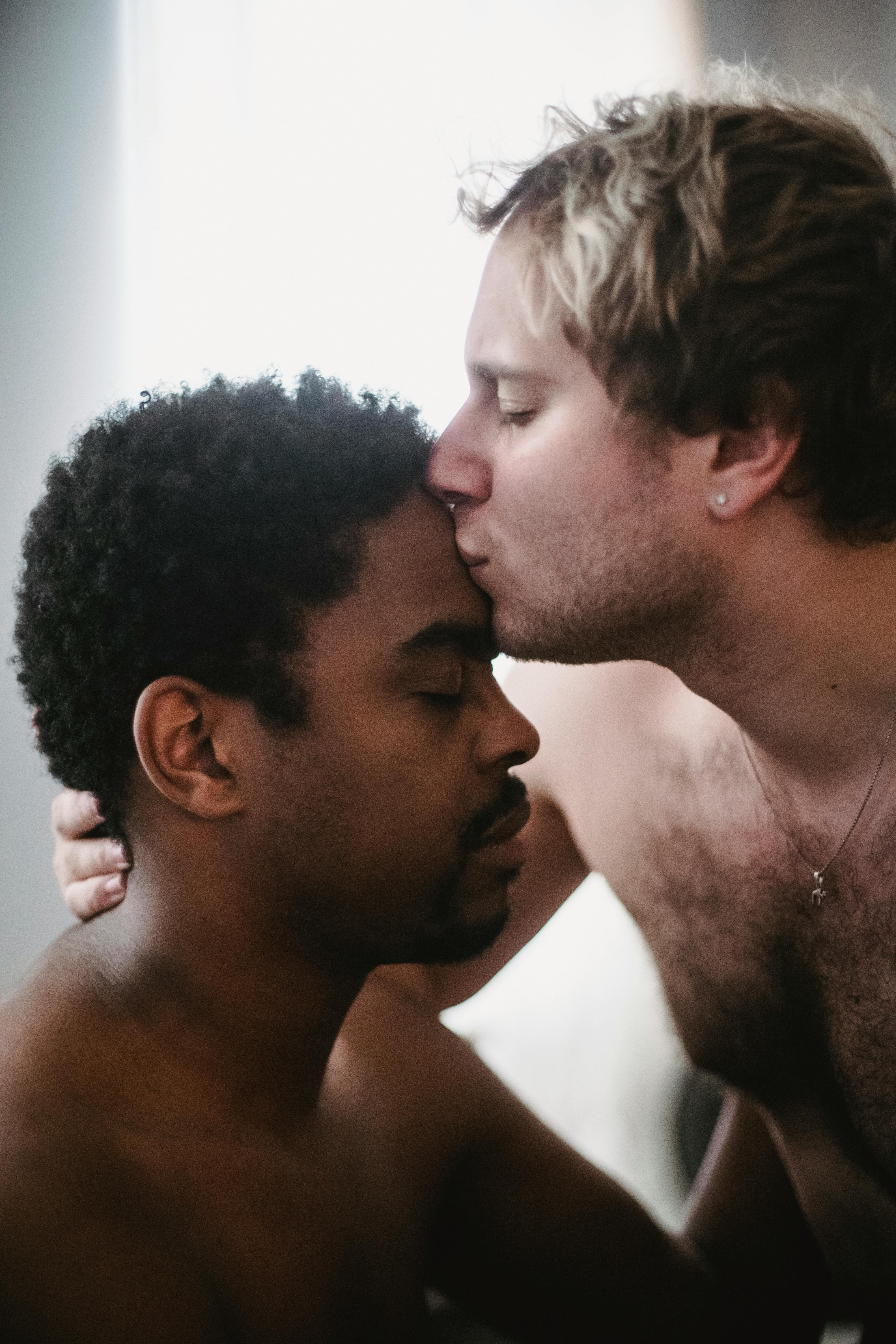 man kissing another man on the forehead