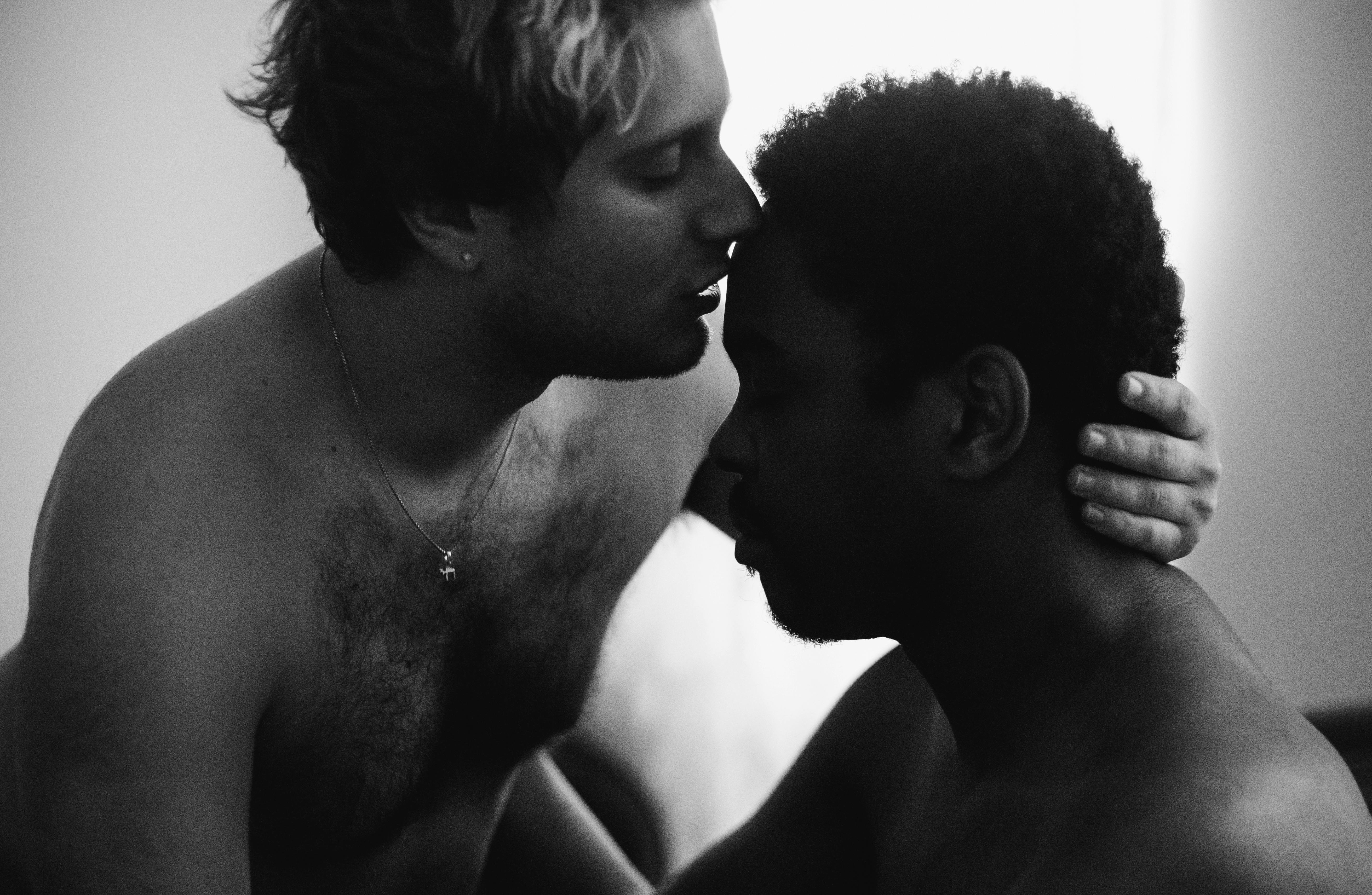 grayscale photo of a man kissing another man on the forehead